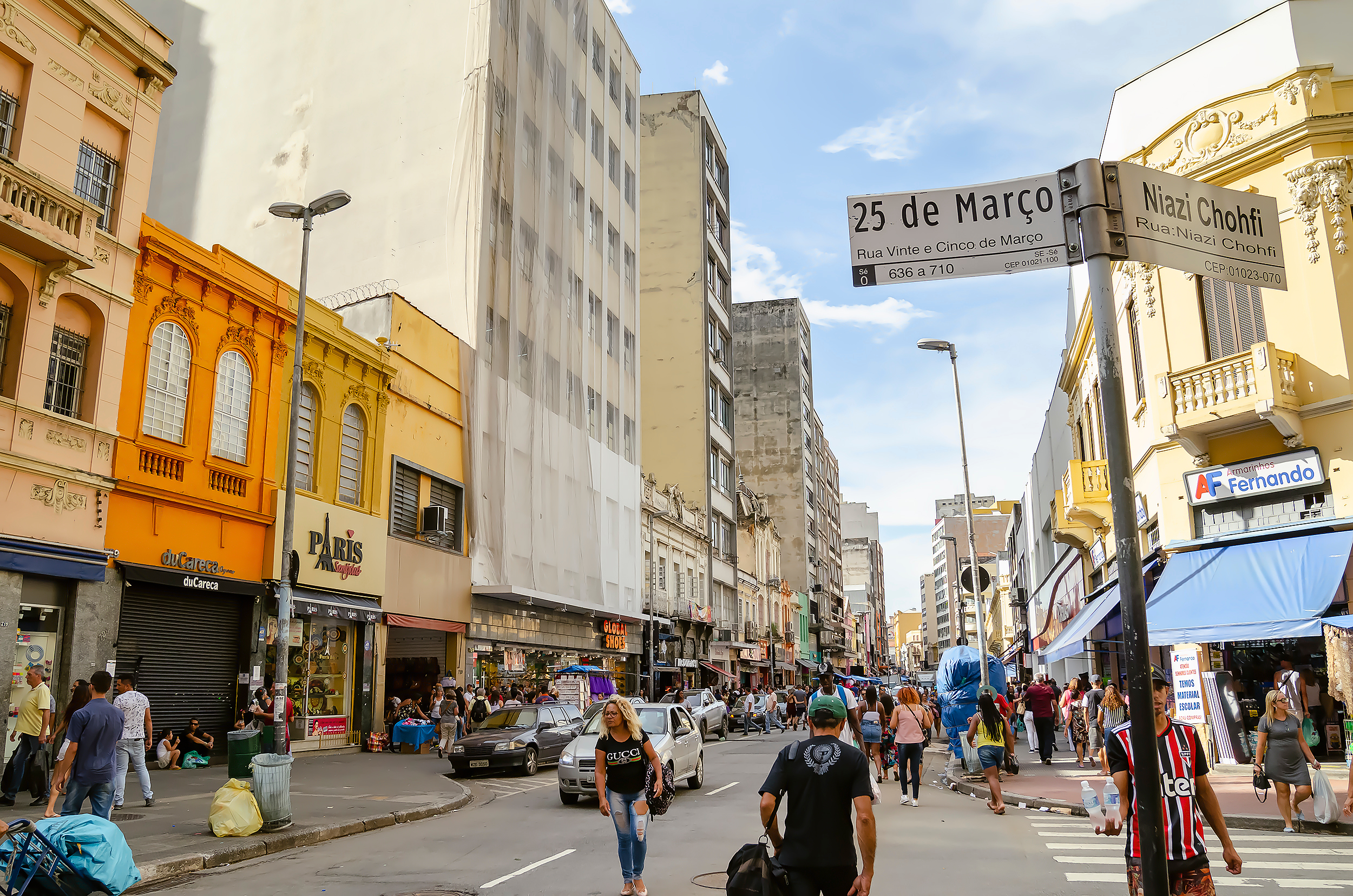 “Movimento na Rua 25 de Março, em São Paulo, com pedestres e comércio ativo; ConectCar facilita o estacionamento na região.