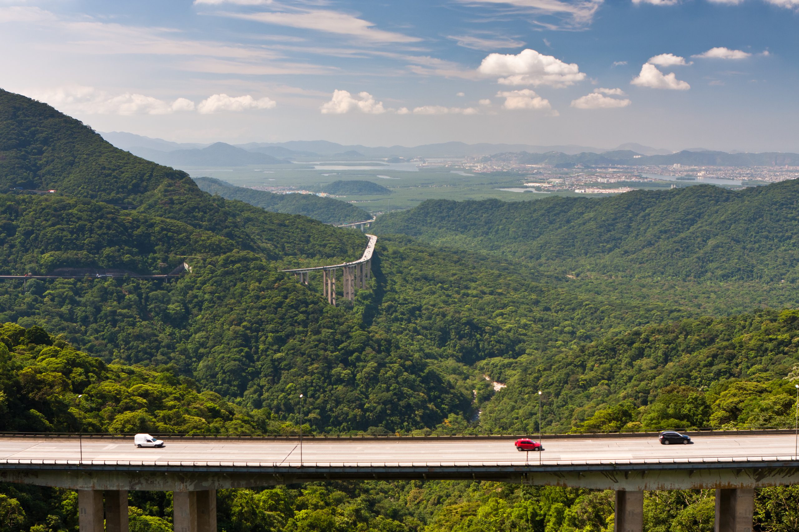 Rodovia Anchieta em trecho de serra com viaduto e veículos em movimento contínuo, cenário do pedágio eletrônico Free Flow com uso da tag ConectCar.