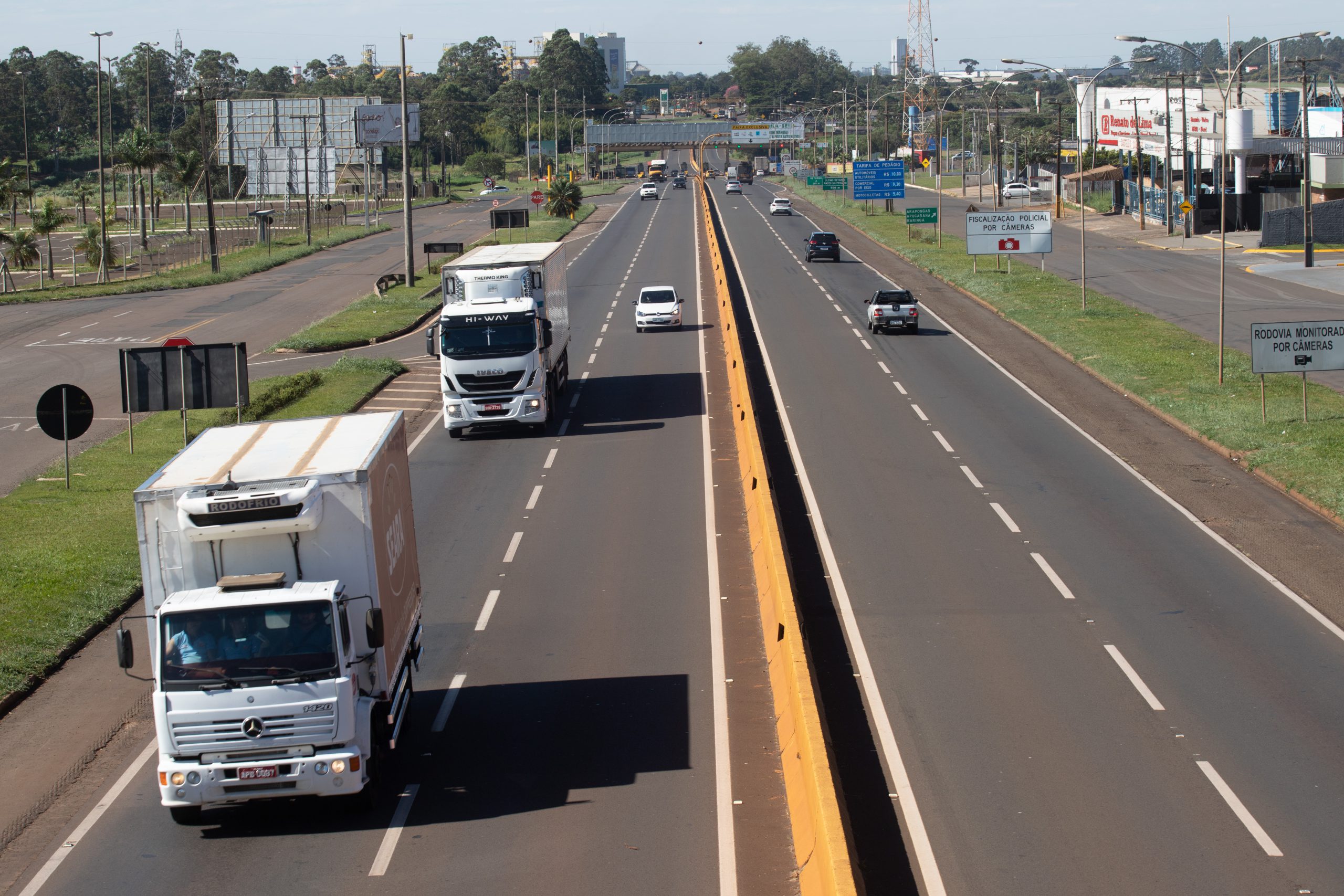 Rodovia movimentada com carros e caminhões em pista duplicada; ConectCar facilita a passagem pelos pedágios e pórticos Free Flow da região