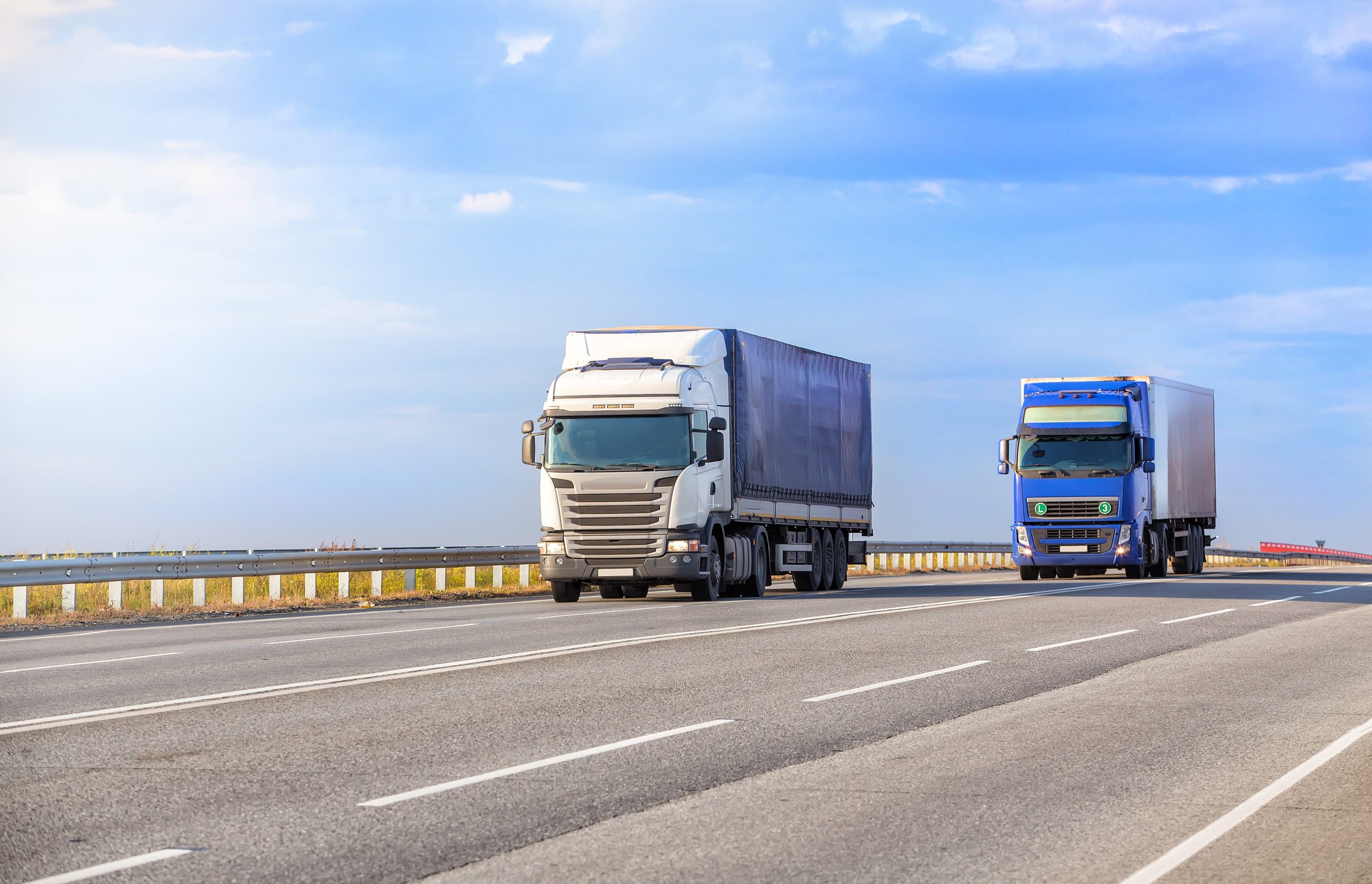 Caminhões trafegando em rodovia durante transporte de cargas, operação que exige pagamento de frete regularizado com CIOT ANTT e solução ConectCar Frete