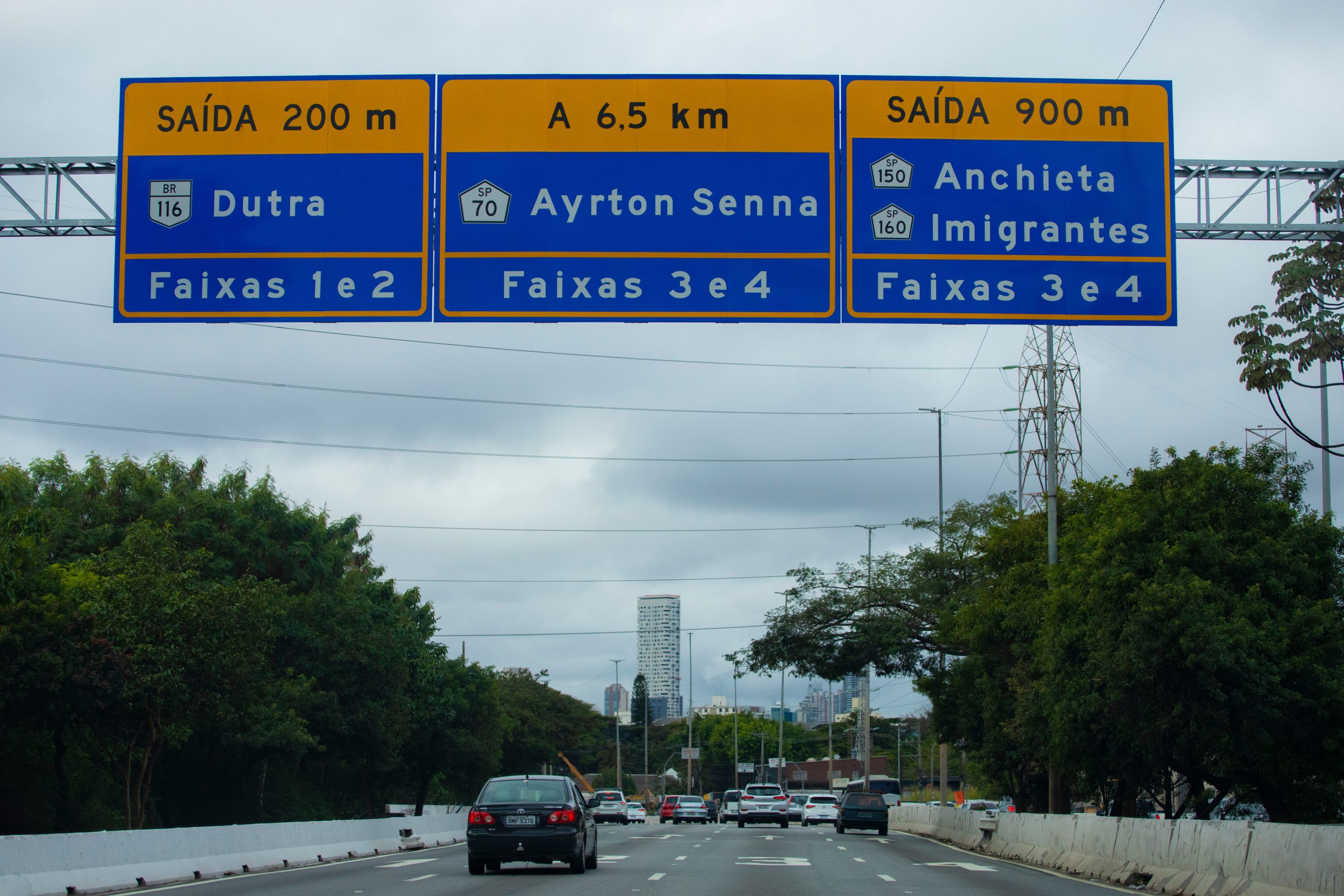 Rodovia em São Paulo com placas indicando saídas para Dutra, Ayrton Senna e Anchieta–Imigrantes; ConectCar facilita a mobilidade nesses trajetos.