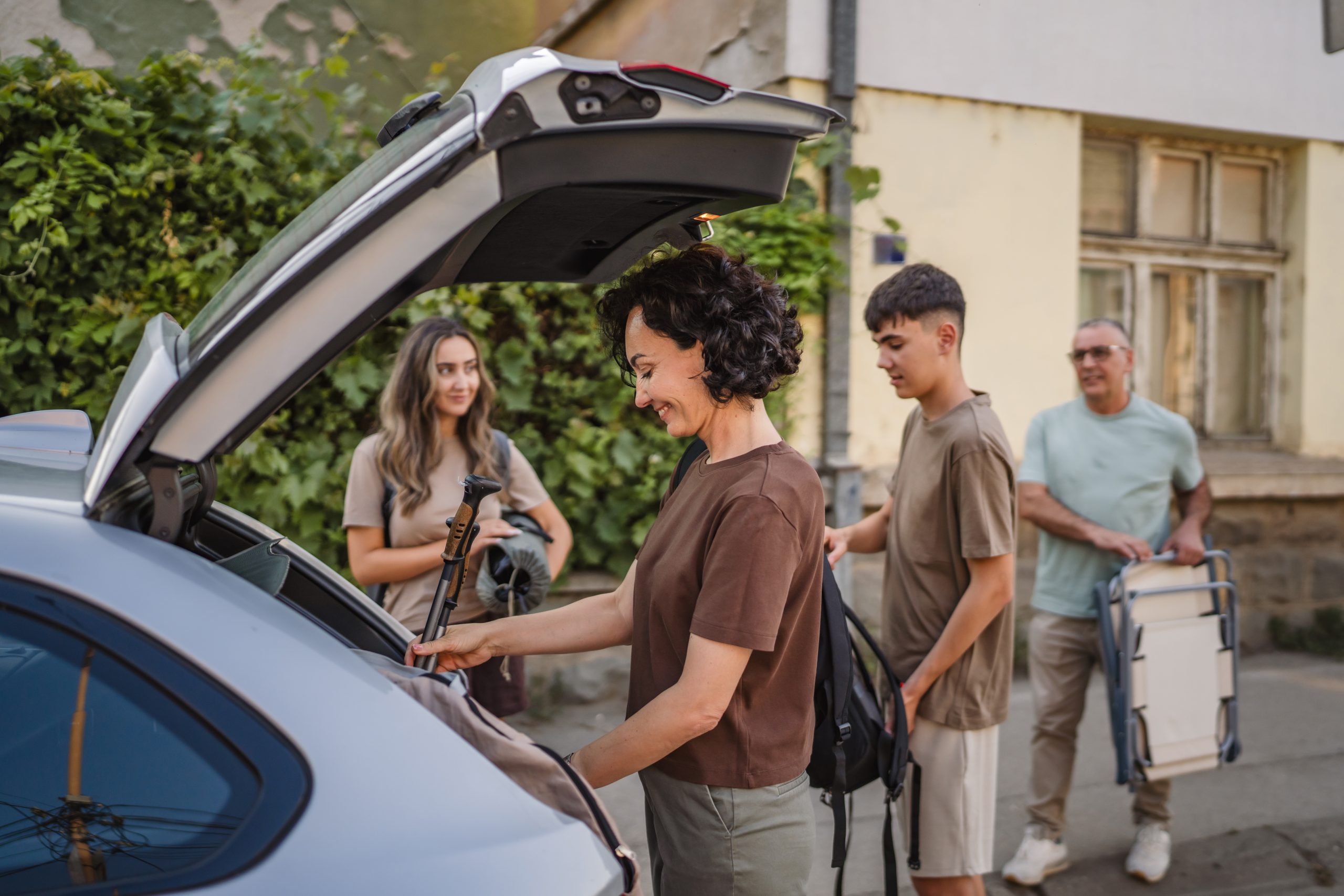 Pessoas organizando bagagens no porta-malas para viagem de carro, com mais praticidade nos pedágios usando a tag ConectCar.
