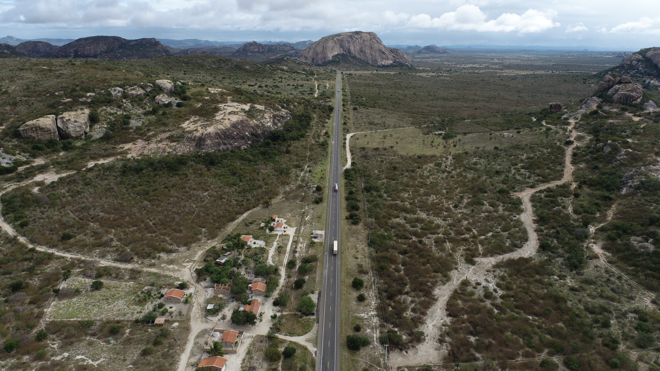 Vista aérea de uma rodovia cortando uma paisagem montanhosa e rural, representando viagens de inverno com praticidade nos pedágios Free Flow usando a ConectCar.